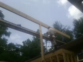 Carpenter setting a ridge beam over a new addition frame — Ice Dam Removal by Roofing Brothers in Murchison