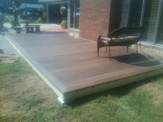 New wood deck and wicker chair beside a brick house in Murchison
