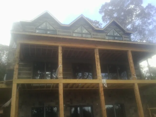 Dormers and porch framing on a large log home under construction — Roof Coating work by our crew in Murchison