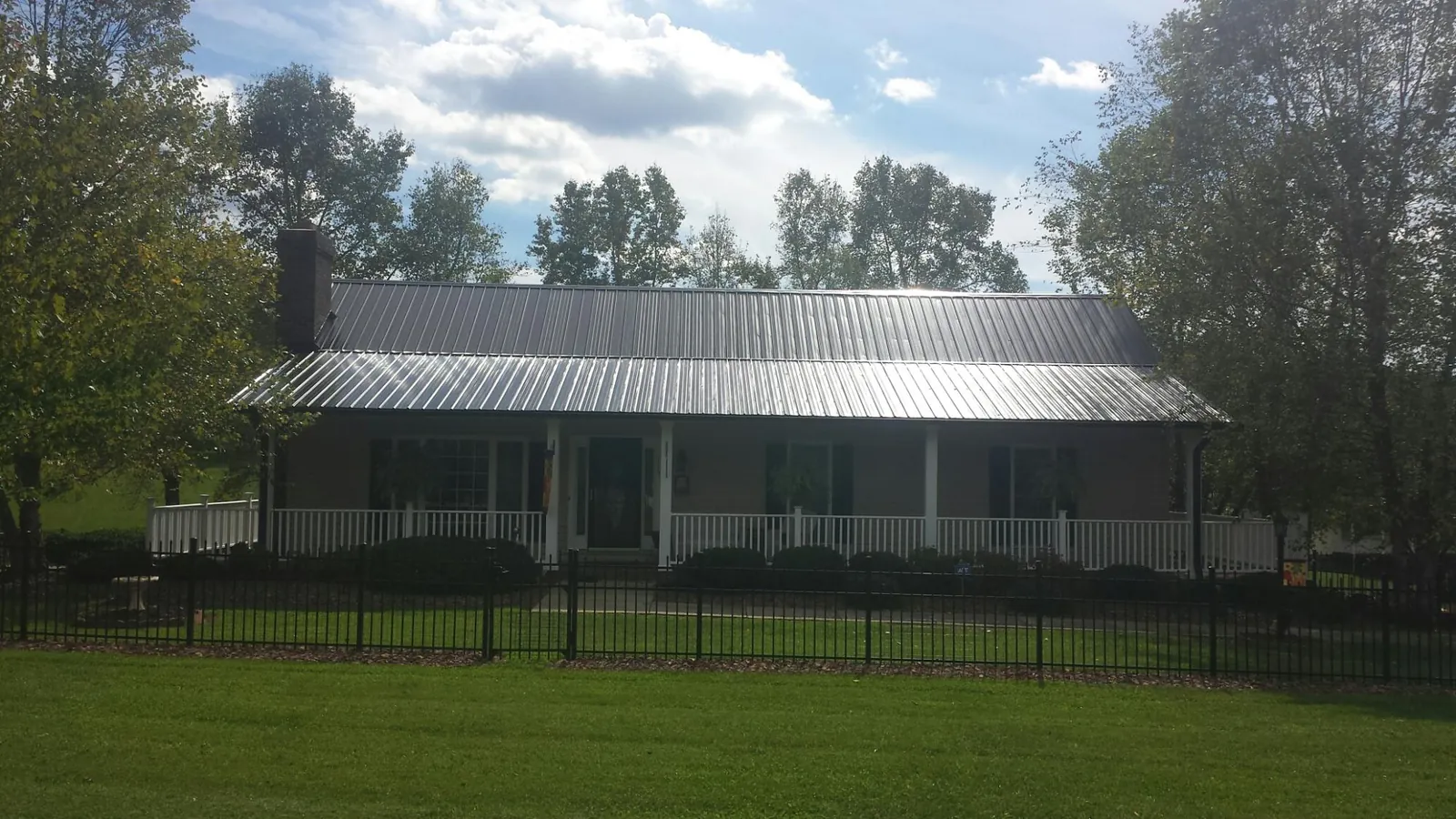 Gray metal roof on a brick ranch with a full width front porch — Gutter Guard Installation work by our crew in Murchison