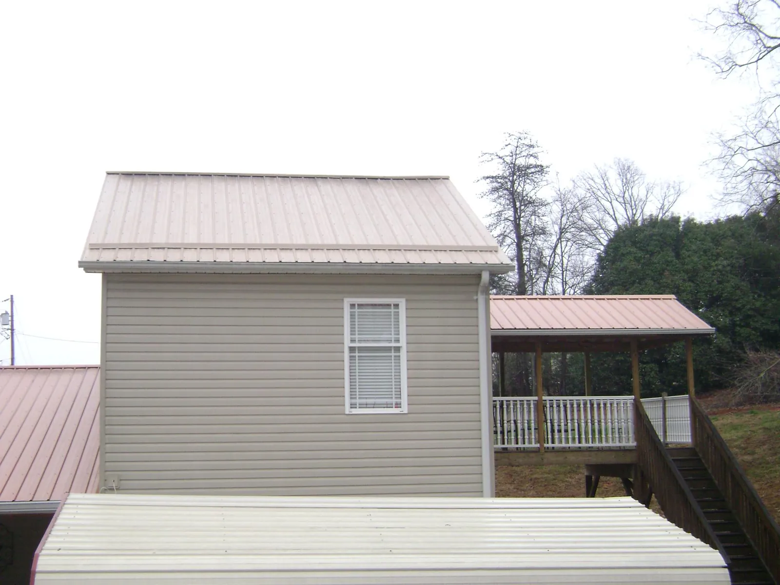 Tan metal roofs on a two story addition and attached porch, from a Roof Replacement job in Murchison