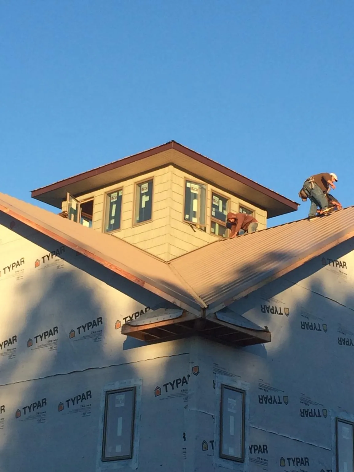 Roofers working around a rooftop cupola on a new metal roof at sunset — Roof Waterproofing in Murchison by Roofing Brothers